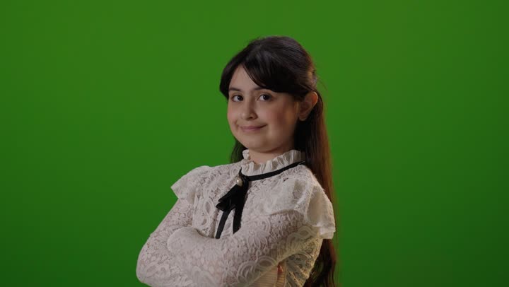 طفلة سعودية تقف مكتوفة اليدين أمام خلفية كروما خضراء