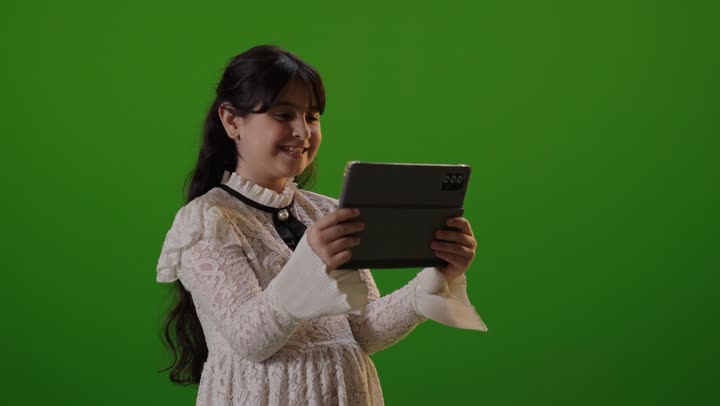 طفلة سعودية تستخدم جهاز لوحي أمام خلفية كروما خضراء