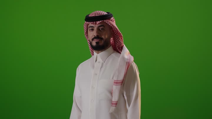 رجل سعودي بالزي التقليدي يشير بالتوقف خلفية خضراء
