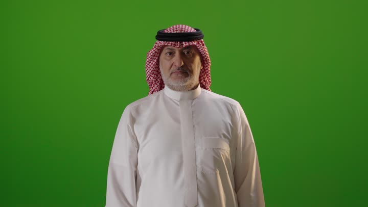 رجل سعودي يشير بالتوقف أمام خلفية خضراء
