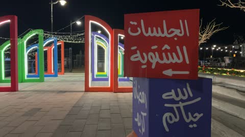 رجل سعودي يسير في فعالية ألوان الجبيل ليلاً