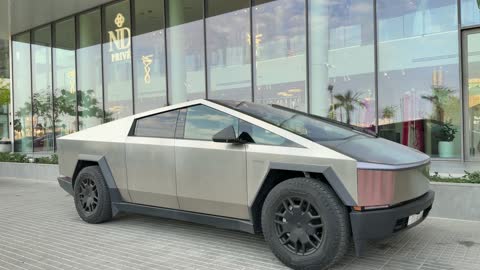 سيارة تسلا سايبرتراك أمام واجهة مبنى حضري حديث