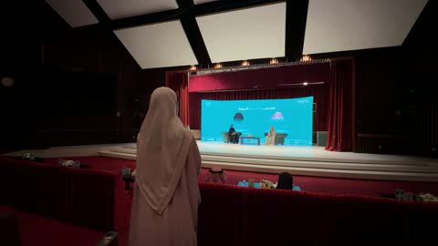 امرأة تشاهد ندوة ثقافية في قاعة المؤتمرات