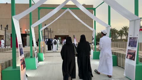 زوار سعوديون يمشون عند مدخل فعالية في الظهران