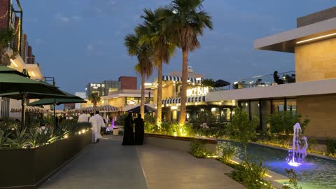 أشخاص سعوديون يمشون في ساحة تسوق خارجية حديثة