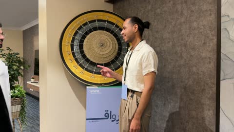 شاب يقف بجانب عمل فني في معرض جامعة الملك فهد