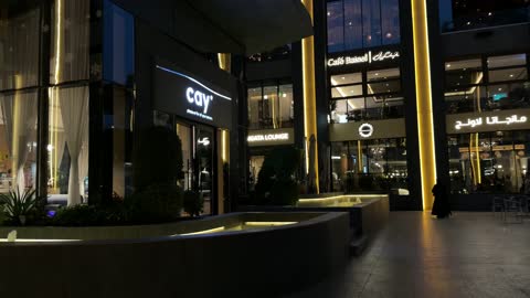 فيديو لساحة تجارية حديثة وواجهات محلات ليلاً
