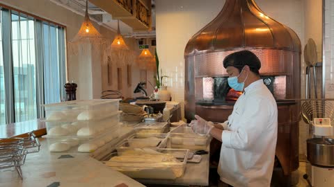 طاهٍ يحضر العجين في مطبخ تجاري وفرن نحاسي