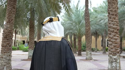 رجل سعودي يمشي في حديقة النخيل لقطة من الخلف