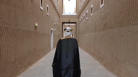 رجل سعودي يمشي في قرية تراثية طينية