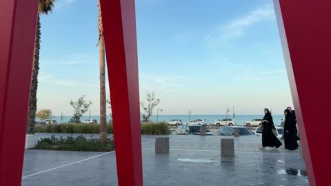 Coastal Promenade with Red Pillars and Palm Trees