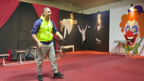A magician is practicing the metal rings trick in an indoor rehearsal.