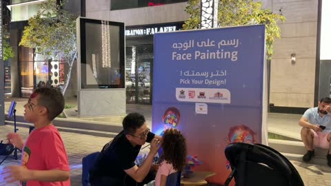 Artist Applying Face Paint to Girl at Night Event