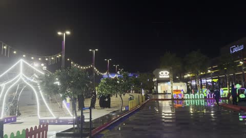 ساحة مركز تسوق خارجي ليلاً مع أضواء النيون