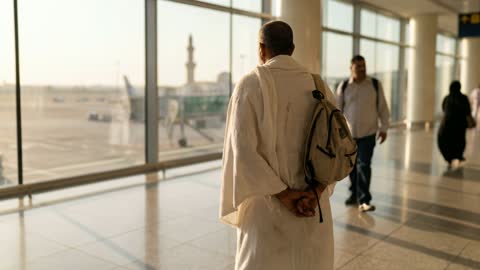 حاج بملابس الإحرام يقف في صالة المطار وقت الغروب