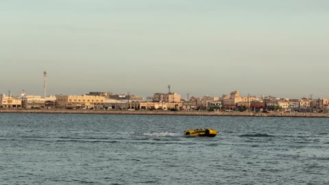 Yellow Amphibious Watercar Speeding in Coastal City Sea