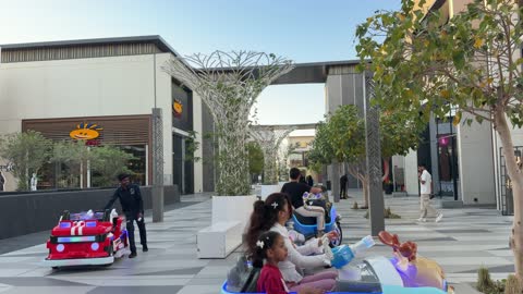Children Riding Electric Cars in Outdoor Shopping Mall