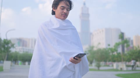 معتمر بملابس الإحرام يستخدم الهاتف الذكي في مكة المكرمة