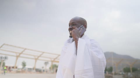 African Muslim Pilgrim in Ihram Talking on Smartphone