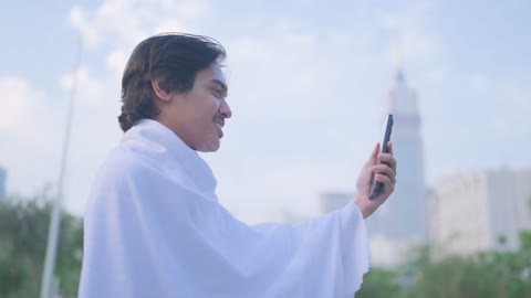 رجل بملابس الإحرام يستخدم الهاتف في مكة