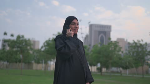 Arab Woman in Abaya Talking on Smartphone in Park