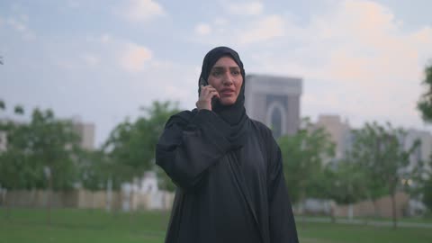 Arab Woman in Abaya Talking on Smartphone in Park