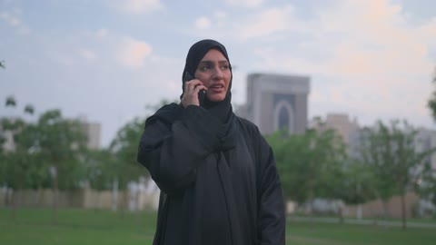 Arab Woman in Abaya Talking on Smartphone in Public Park