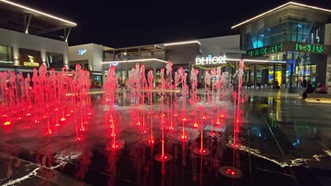 Red Illuminated Water Fountain in Urban Plaza at Night