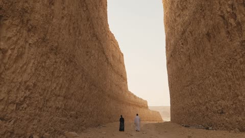 Man and Woman Walking Through Narrow Desert Canyon