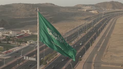 علم المملكة العربية السعودية يرفرف فوق طريق سريع