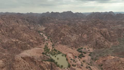 مشهد جوي لبحيرة ووادي جبلي صخري في الصحراء في حائل