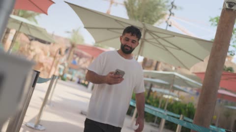 Man Walking in Outdoor Theme Park with Smartphone