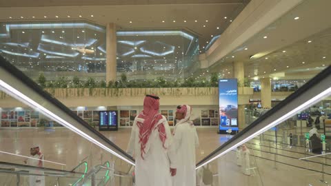 رجال سعوديون على السلم المتحرك في مطار الرياض الدولي