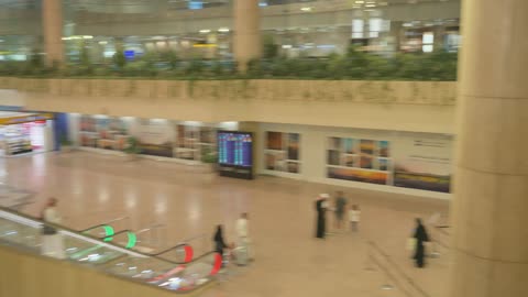 مبنى مطار سعودي من الداخل مع سلالم ومسافرين