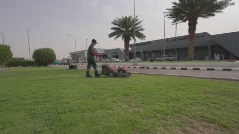 عامل يقص العشب في مطار القيصومة بالمملكة العربية السعودية