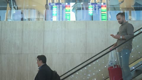 مسافرون ورجال أعمال على سلم كهربائي في المطار