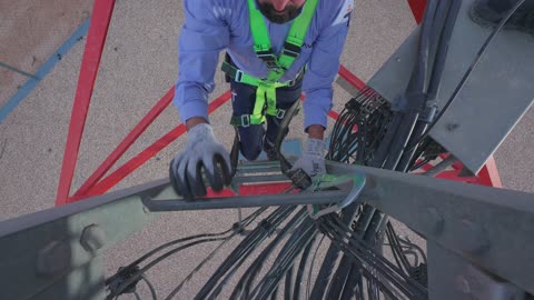 Technician Climbing Telecom Tower With Safety Harness