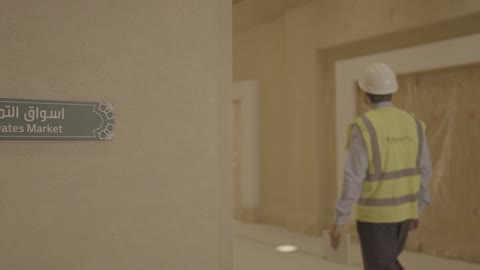 مهندس يسير بالقرب من لوحة أسواق التمر