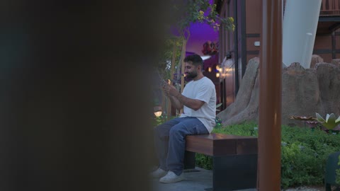 Man Using Smartphone on Bench at Theme Park Night