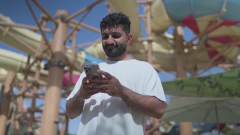 Man Using Smartphone at Water Park Daylight Footage