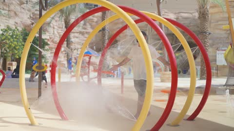 Man Standing Under Water Park Sprinkler Arch