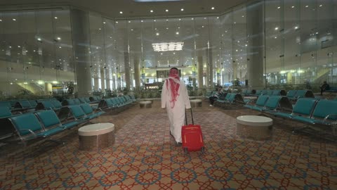 Saudi Man Walking in Airport Terminal with Red Suitcase