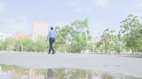 رجل يمشي في حديقة المدينة مع حمام وانعكاس مائي