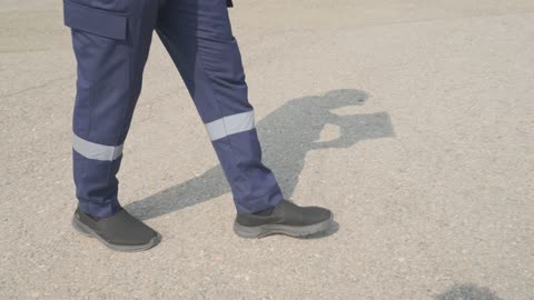 Worker in Uniform Walking on Asphalt with Shadow