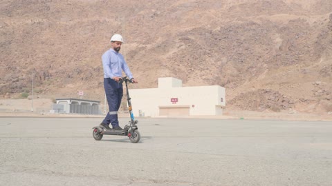 Arab Engineer Riding Electric Scooter at Industrial Site