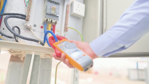 Electrician Using Clamp Meter on Electrical Panel