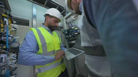Technicians Inspecting Data Center Servers with Laptop