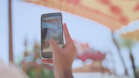 شخص يحمل هاتف ذكي يستخدم تطبيق سناب شات في الخارج