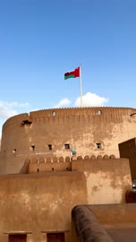 قلعة نزوى التاريخية في سلطنة عمان مع علم البلاد يرفرف