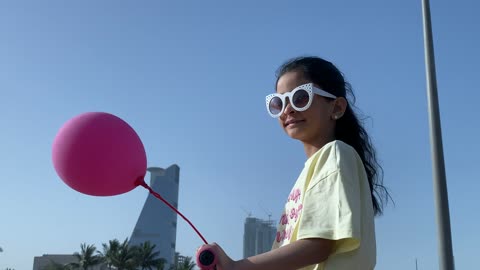 Girl Riding Scooter at Jeddah Corniche with Pink Balloon